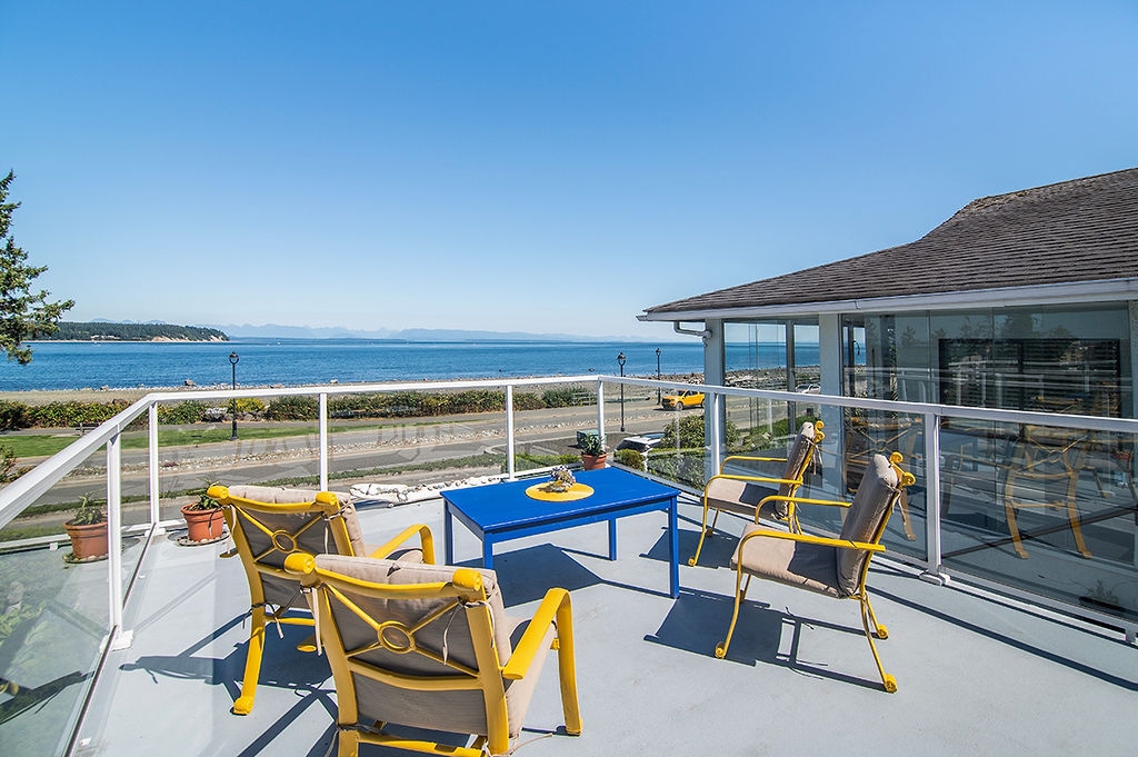 The Whale House deck with yellow chairs overlooking the ocean and coastal mountains